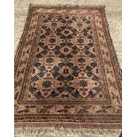 A wool rug with fringed ends. Brown ground with blue and brown geometric style pattern.