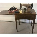 A vintage dark wood cased table tredle singer sewing machine together with a quantity of accessories