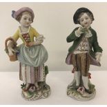 A pair of Sitzendorf German ceramic figurines of a boy and a girl carrying a flower basket.