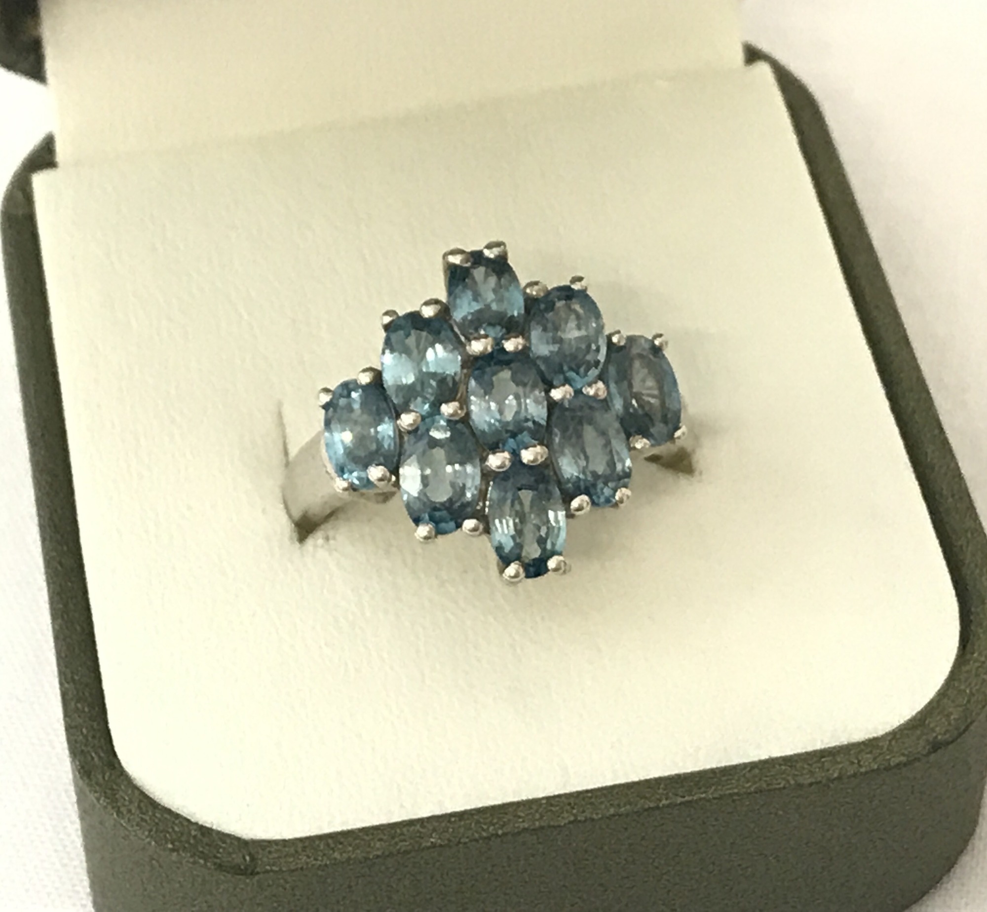 A ladies dress ring set with 9 oval cut blue topaz stones.