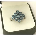A ladies dress ring set with 9 oval cut blue topaz stones.
