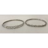 2 ladies silver bangles both set with cubic zirconia stones.