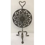 A Victorian metal fire screen. A circular pierced work revolving disc raised on tripod feet.