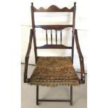 A vintage folding dark wood chair with carpet seat and spindle decoration to back.