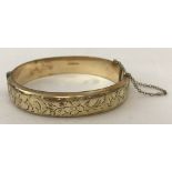 A vintage 9ct rolled gold hinged bangle with half engraved decoration and safety chain.