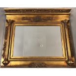 A large gilt framed over mantle mirror with column detail and floral decoration to frame.