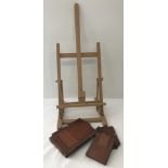 A small light wood artists easel together with a collection of vintage wooden cases