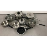 A tub of assorted modern stainless steel saucepans.