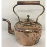 A large antique copper kettle with tall, shaped handle.