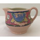 A Royal Staffordshire ceramics Clarice Cliff milk jug in pink with painted design detail.