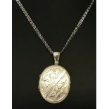 A vintage white metal locket with ivy engraved detail to front and floral decoration to back.