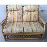 A 2 seater cane conservatory settee with natural coloured cushions.