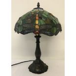 A Tiffany style table lamp with dragonfly detail to multi-coloured metal and glass shade.
