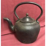 A heavy cast iron kettle with curved handle and spout.