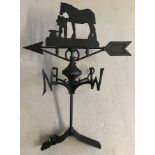 A back cast iron weather vane with horse and blacksmith detail.