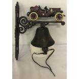 A cast iron wall hanging garden bell with motorcar detail.