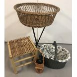 A large circular wicker basket on a black metal three-legged stand.