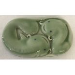 A green porcelain Chinese scroll weight depicting fish.