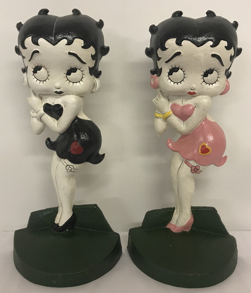 2 painted cast iron Betty Boop doorstops; one in black and white, the other in pink.