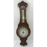 A vintage oak cased barometer and thermometer with carved detail to front.