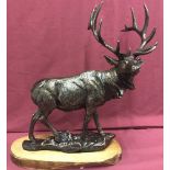 A large cast metal figure of a Stag mounted on a wooden base.