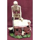 A painted cast iron money box of a skeleton cutter, with moving parts.
