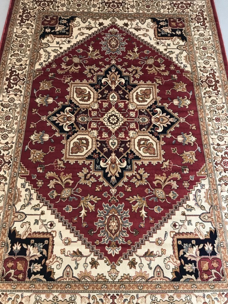 A Heriz pattern rug; red background with blue, beige and gold colouration.