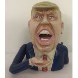 A cast iron novelty money bank in the shape of Donald Trump, with moving arm action.