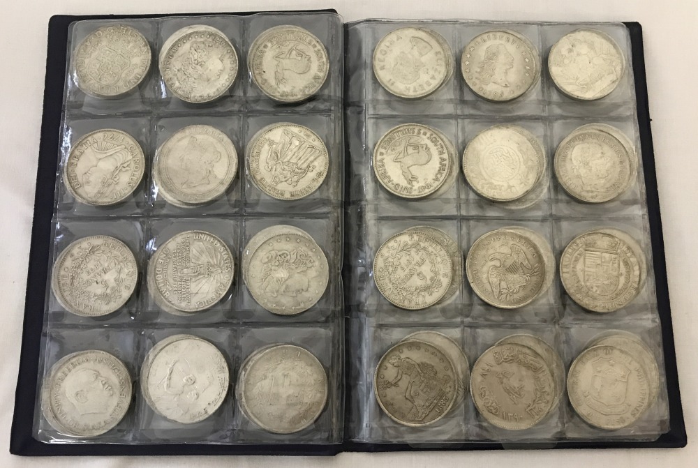 A folder containing 72 assorted white metal coins from around the world.