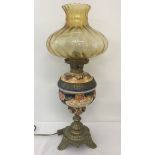 A vintage ceramic and brass lamp base with amber glass shade.