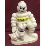 A heavy cast iron figure of the Michelin Man and dog, painted white.