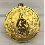 A large silver gilt pendant with partridge and pear tree decoration.