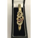 A 9ct gold, ruby and diamond set, hinged bangle.