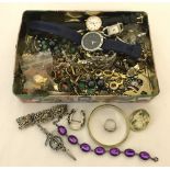 A tin of mixed costume jewellery and dress watches.