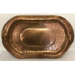 A large antique copper tray with hammered detail and etched initials in central panel.