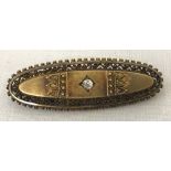 A vintage decorative oval shaped brooch set with a single round cut diamond. Tests as 9ct.
