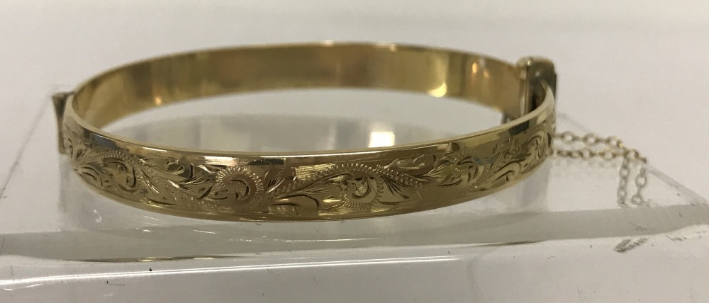 A vintage 9ct rolled gold, half engraved, hinged bangle with safety chain.