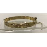 A vintage 9ct rolled gold, half engraved, hinged bangle with safety chain.