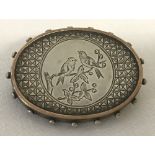 A Victorian white metal mourning brooch with decorative panel to front depicting birds in a tree.