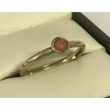 A 9ct gold ladies dress ring, set with a small round coral stone.