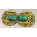 A vintage gold tone belt buckle set with turquoise stones and filigree detail.