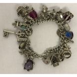 A vintage silver charm bracelet with 26 silver and white metal charms.