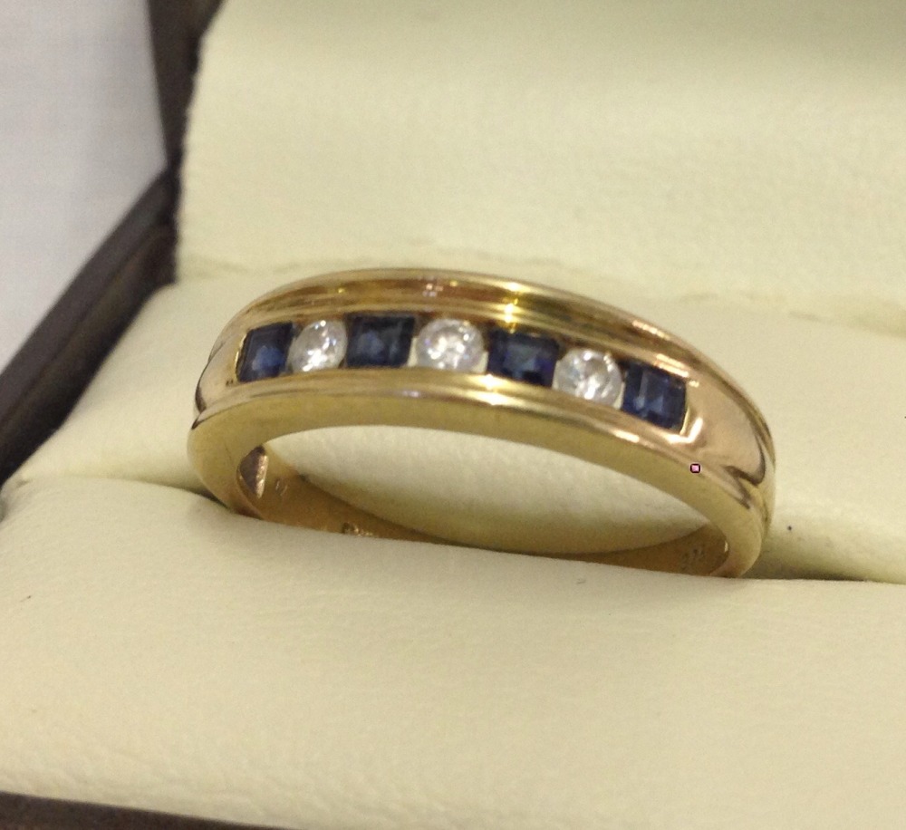 A 9ct gold dress ring with channel set sapphires and clear stones.