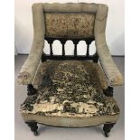 A Victorian ebonised and upholstered armchair on ceramic castors.