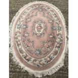 A small oval floral rug with fringed ends.