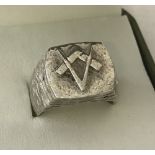A men's heavy white metal ring with Masonic square and compass design to top.