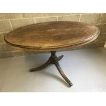 An oval dining table with marquetry decoration in centre of top.