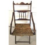 A vintage folding dark wood chair with carpet seat and spindle decoration to back.