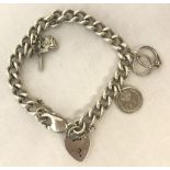 A silver charms bracelet with white metal and silver charms, padlock and safety chain.