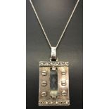 A large white metal contemporary design pendant set with a faceted clear stone.